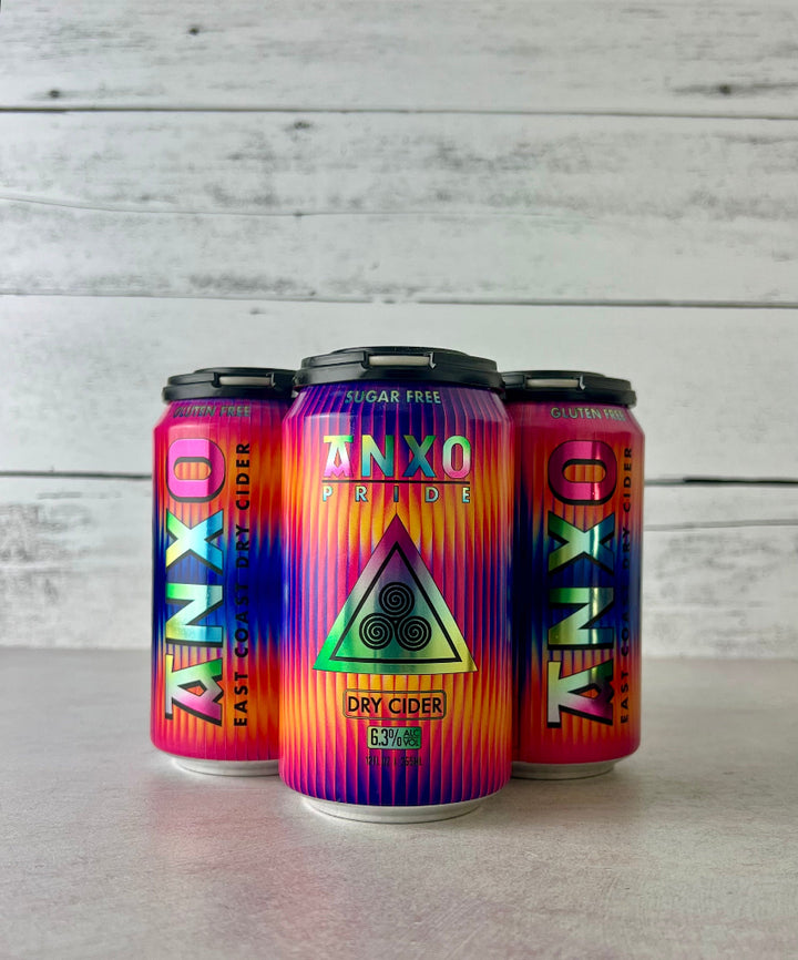 photo of a 4-pack of 12-oz cans of Anxo Pride dry cider with a colorful design on a white wooden background