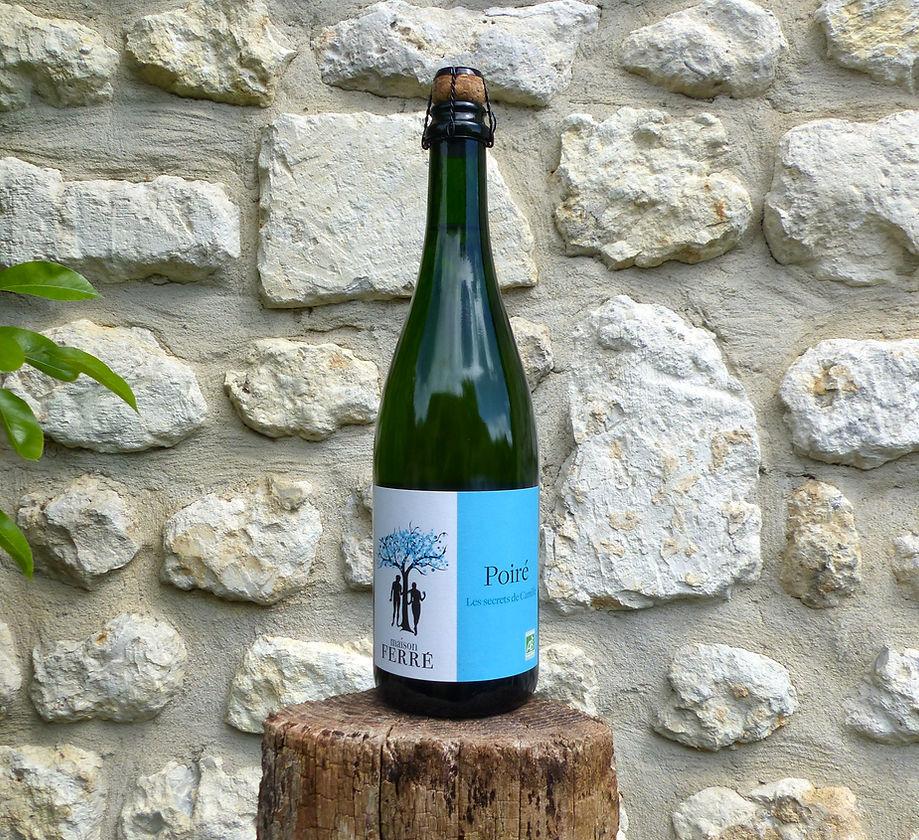 750 mL bottle of Maison Ferré Poiré on a log in front of a white rock wall