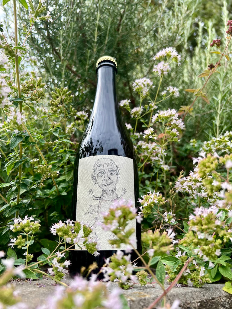 750 mL bottle of Eve's Cidery Dabinett cider surrounded by flowering herbs