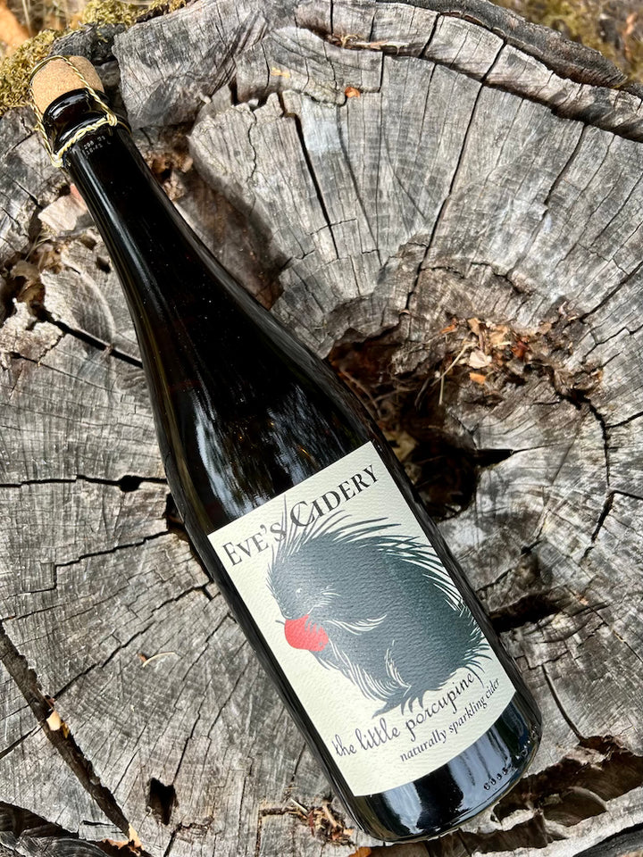 750 mL bottle of Eve's Cidery the little porcupine - naturally sparkling cider - bottle lying on a stump