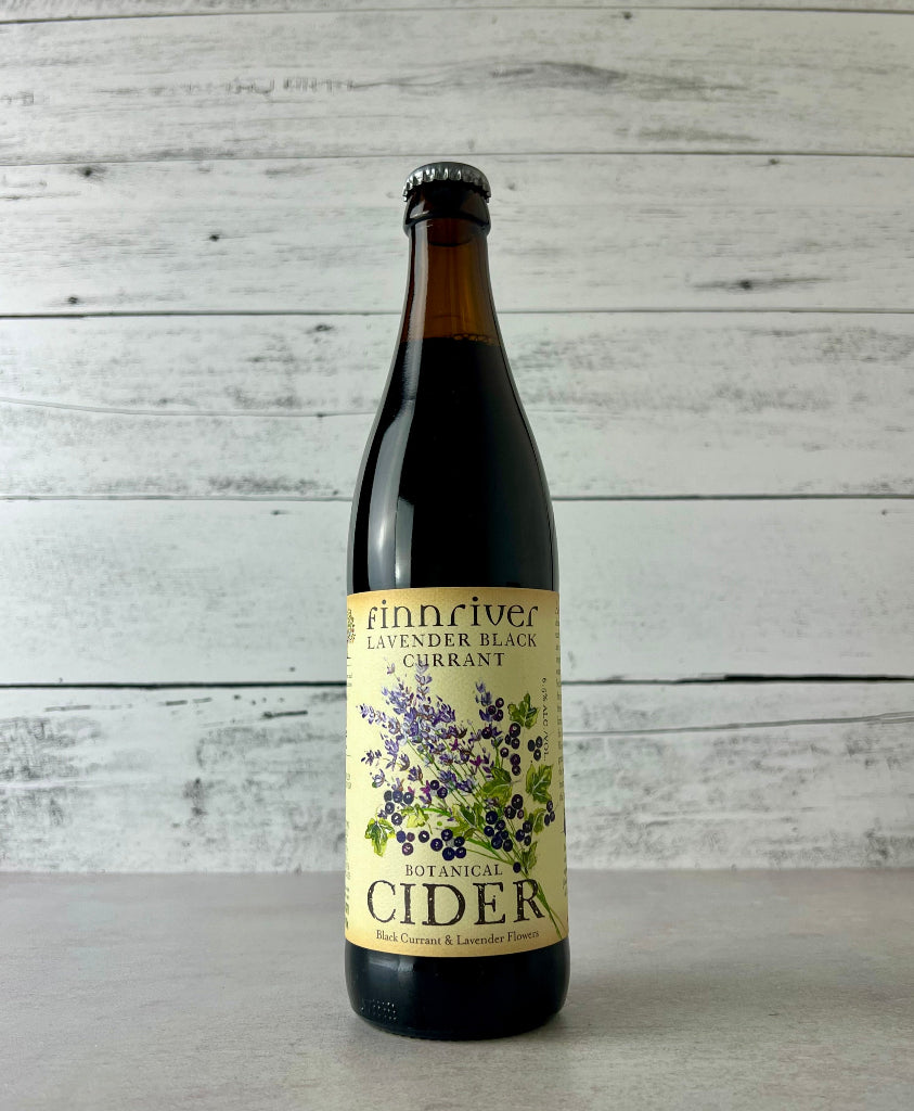 Photo of a 500 mL Bottle of Finnriver Lavender Black Currant cider on a white wooden background