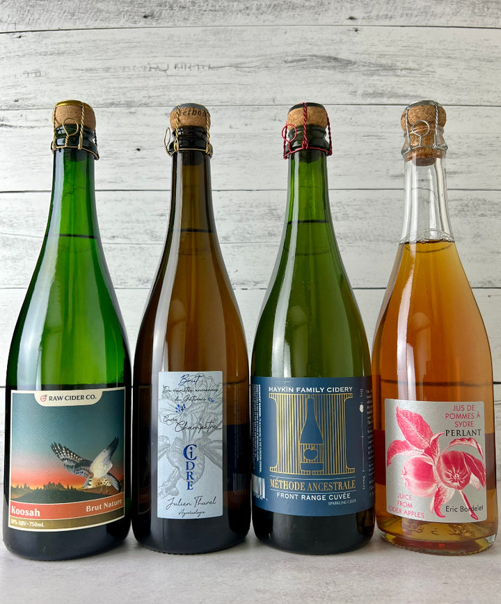 Photo of 4 bottles of cork and caged sparkling ciders: RAW Koosah Brut Nature, Julien Thurel Cidre Champêtre Cidre Extra Brut, Haykin Family Cider Front Range Cuvee, and Eric Bordelet Jus de Pommes A Sydre Perlant Juice from Cider Apples