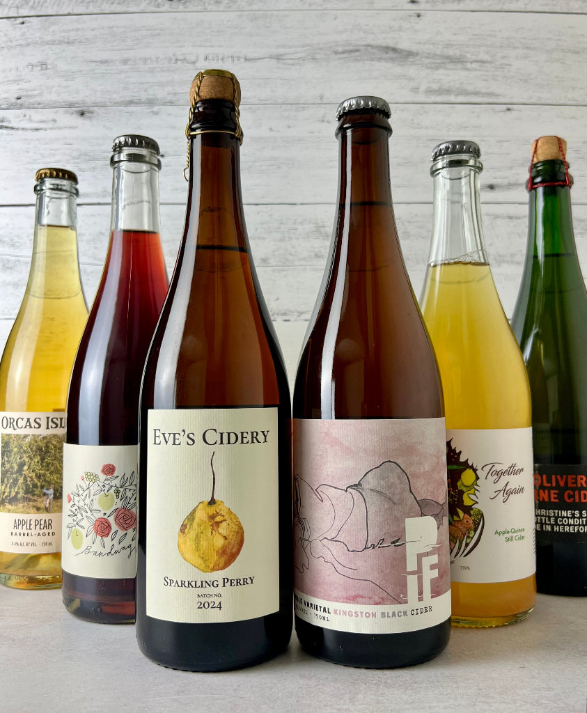 Photo of 6 750 mL bottles of cider, including Orcas Isle Apple Pear, Rose Hill Farm Bandwagon, Eve's Cidery Sparkling Perry, PIF Single Varietal Kingston Black Cider, Durham Together Again Apple/Quince Still Cider, Oliver's Fine Cider