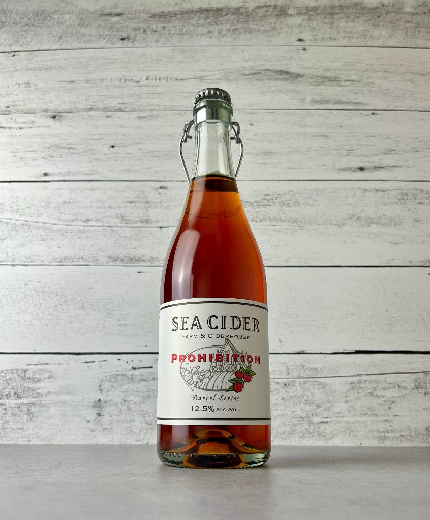 750 mL clear glass bottle of copper colored Sea Cider Farm & Ciderhouse Prohibition Barrel Series cider with flip top