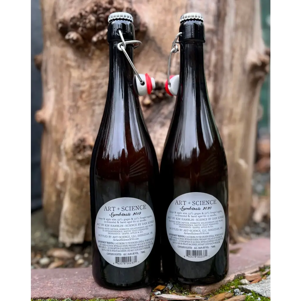 Two bottles of Art & Science Symbiosis cider showing the back labels. One label says 2019 and the other says 2020.