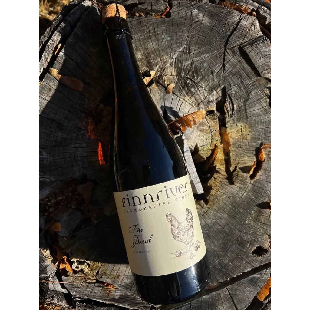 Bottle of Finnriver Fire Barrel cider laying on a stump