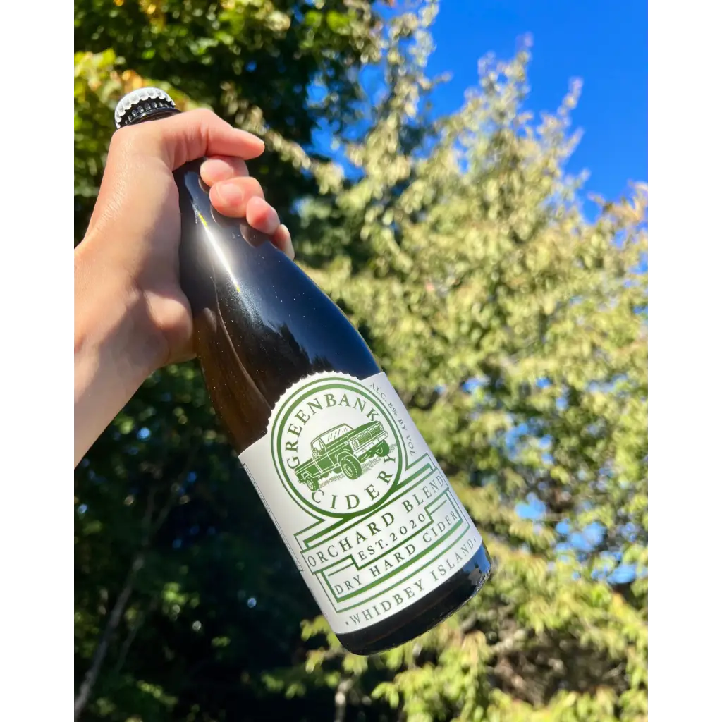 500 mL bottle of Greenbank Cidery Orchard Blend Dry Hard Cider - Whidbey Island - with blue sky and tree in background