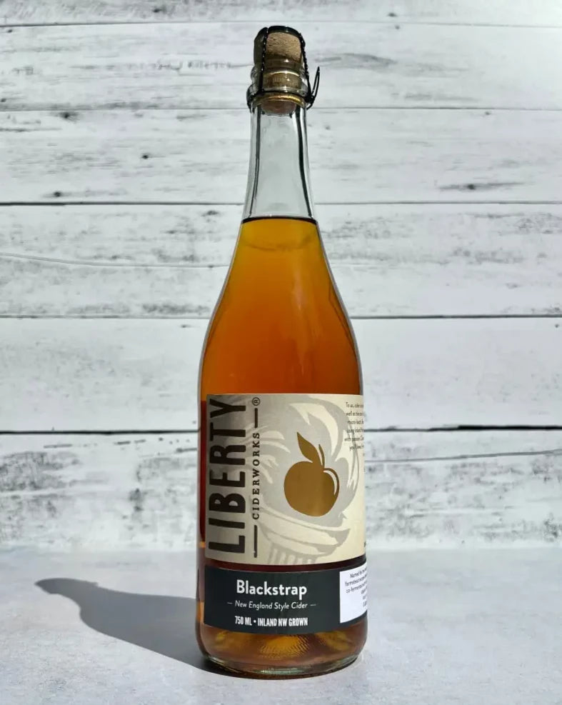 750 mL clear glass bottle of amber hued Liberty Ciderworks Blackstrap New England Style Cider