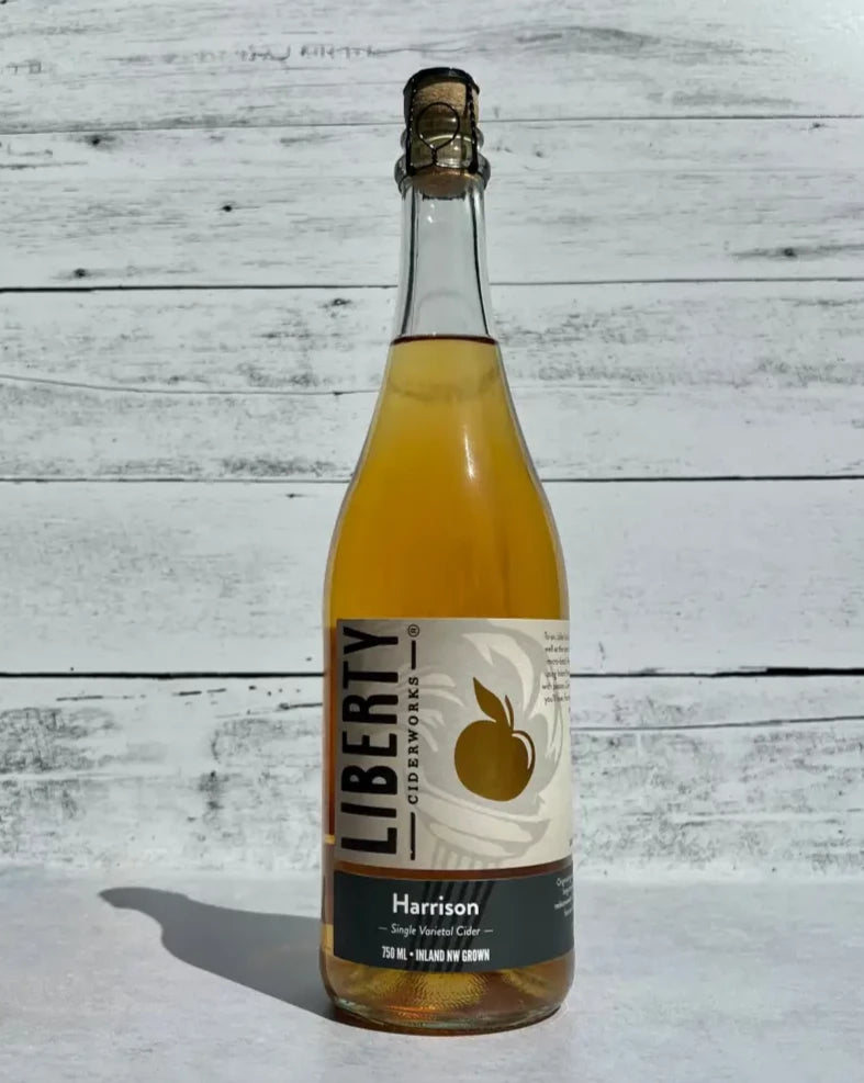 750 mL clear glass bottle of Liberty Ciderworks Harrison Cider with cork and cage top